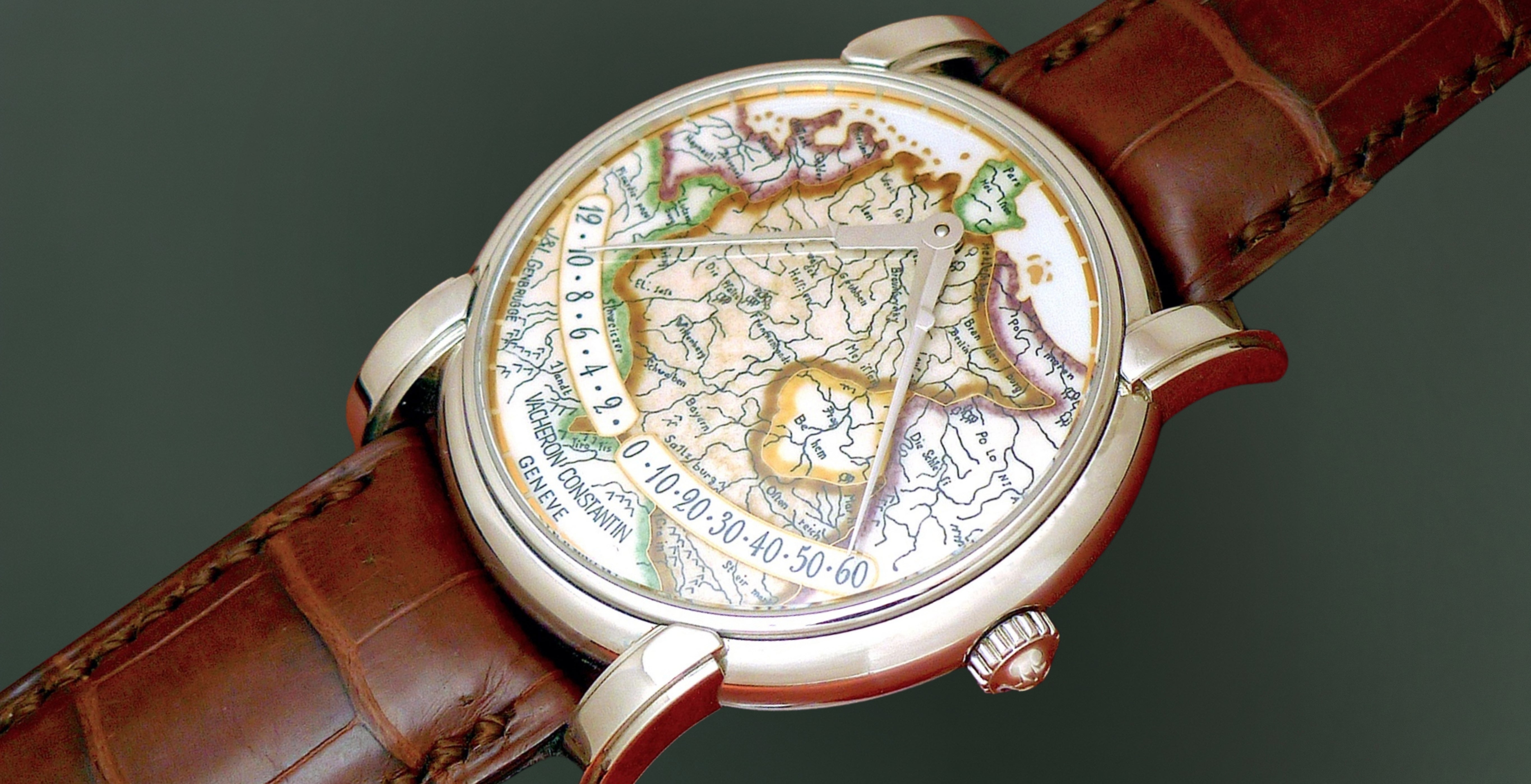 Close-up of a Vacheron Constantin Mercator wristwatch with a hand-painted map dial, retrograde time display, polished gold case and brown leather strap