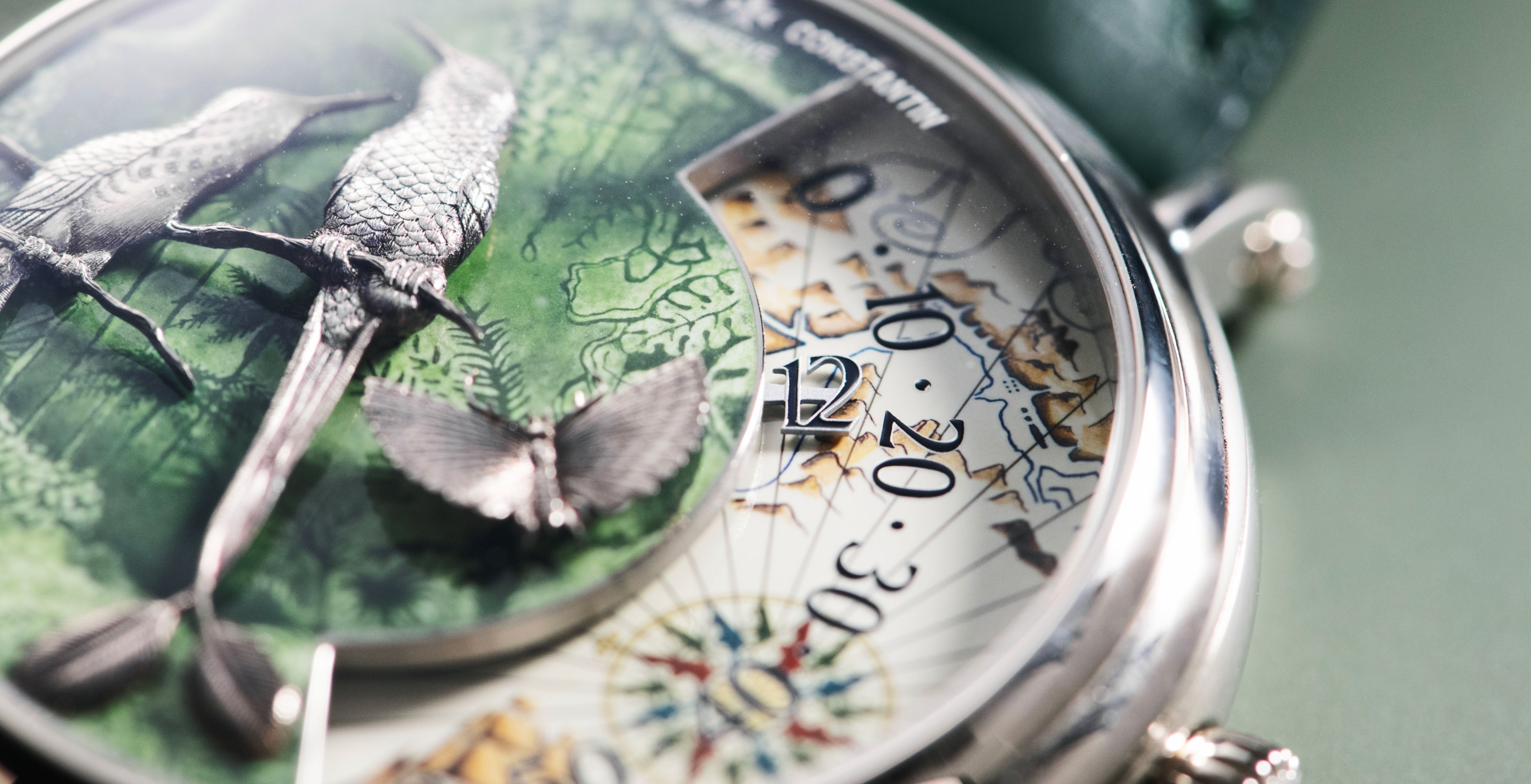 Macro view of the Vacheron Constantin Métiers d’Art Terre de Feu dial, highlighting hand-engraved white-gold birds and a butterfly over green enamel, beside the wandering-hours display.