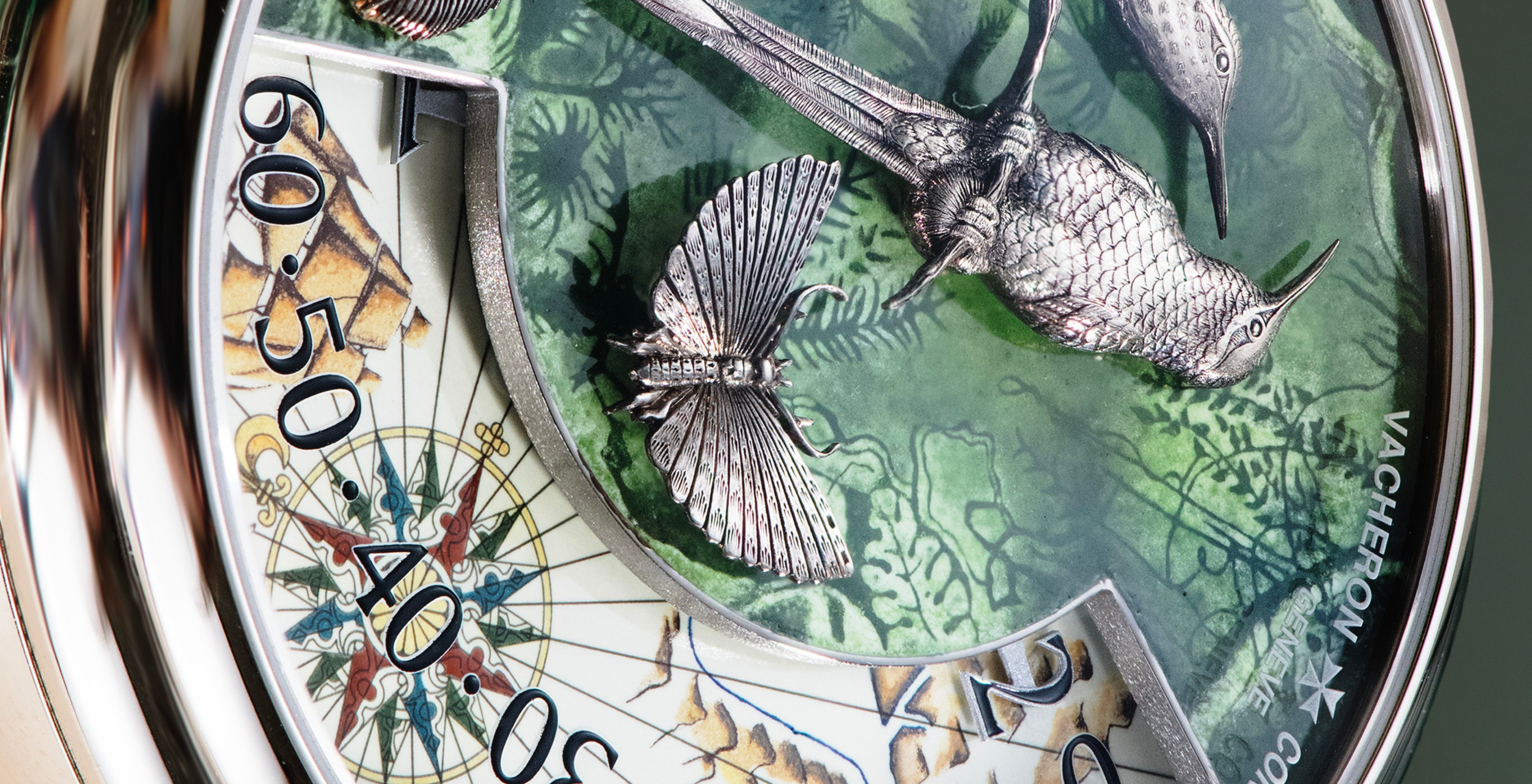 Detailed view of the Vacheron Constantin Métiers d’Art Terre de Feu dial, featuring hand-engraved white-gold birds and a butterfly over green enamel, with a map and compass-inspired minute scale.